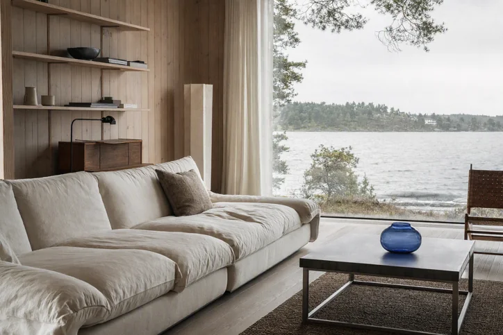 Scandinavian lakeside living room. Professional interior photography with cool natural daylight and subtle film grain.