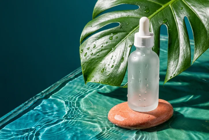 Skincare still life. Bold macro product photography with jade green, cyan water and crisp caustic light.